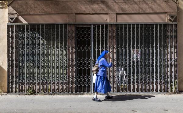 Nonne en robe bleue se dépêche dans la chaleur de midi le long du sentier — Photo