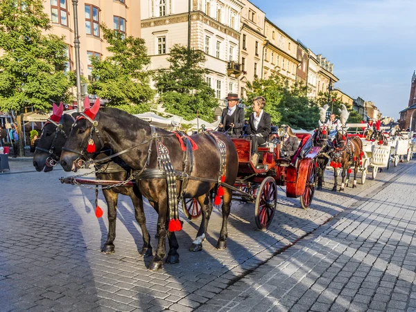 Carruagens de cavalo em frente à igreja Mariacki na praça principal de Kr — Fotografia de Stock