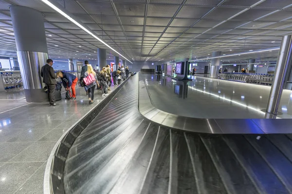 Lidé čekají na zavazadla u zavazadlových pásů na letišti ve Frankfurtu — Stock fotografie