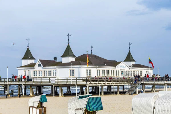 ドイツのAhlbeck ドイツ エイプリル社2014年20日 ドイツのヘリングドルフの桟橋とビーチを楽しむ人々 宇土島のバルト海は そのユニークな屋根のウィッカービーチチェアで有名です — ストック写真