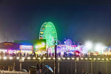 Santa Monica, ABD - 16 MAR 2019: İnsanlar geceleri Santa Monica rıhtımındaki okyanus parkının tadını çıkarıyorlar. Alan, California 'lı ziyaretçiler için 100 yıllık sembolik bir simge..