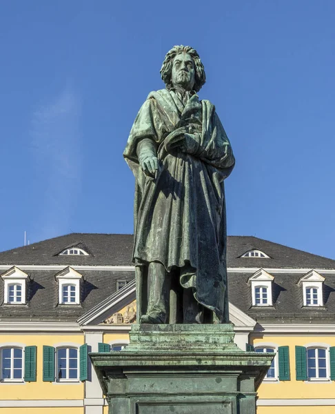A statue of famous composer Ludwig van Beethoven - with the beautiful Old Post Office building in the background, located on Munsterplatz in the city of Bonn in Germany.