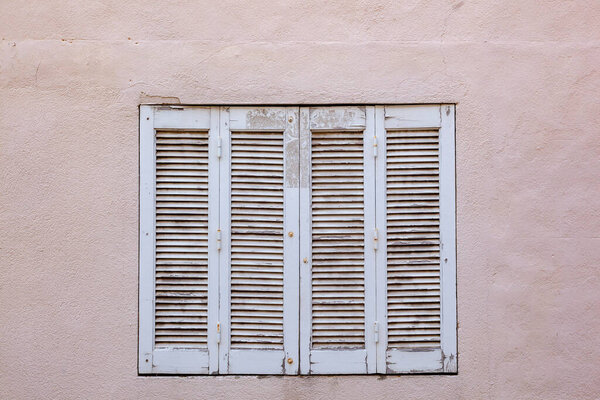 Old house with wooden window shutter and peeling paint as background
