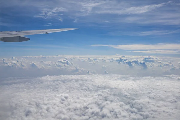 飛行機の窓から外を見ると空は真っ青で小さな雲が — ストック写真