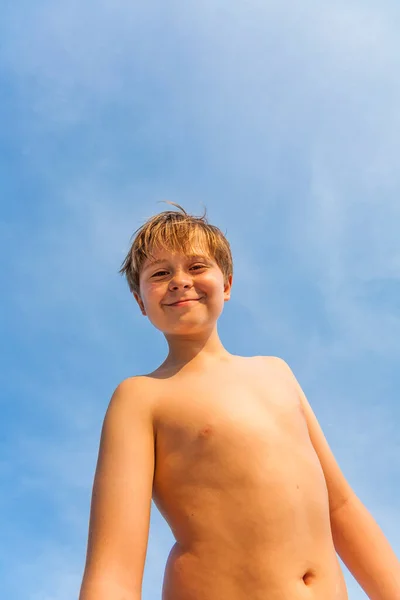 在蓝天的背景下 在海滩上快乐地微笑着的小男孩 — 图库照片