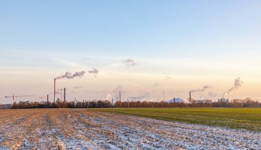 Geceyarısı Frankfurt 'ta tarlalar ve kışın tüten bacalarla sanayi kompleksi