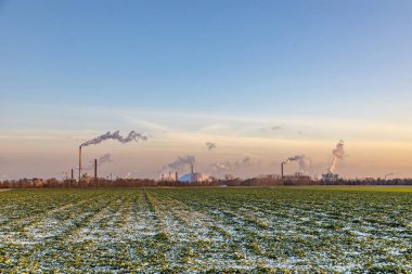Geceyarısı Frankfurt 'ta tarlalar ve kışın tüten bacalarla sanayi kompleksi