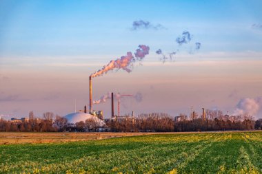 Geceyarısı Frankfurt 'ta tarlalar ve kışın tüten bacalarla sanayi kompleksi