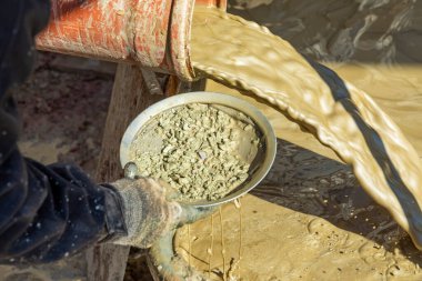 Yapay bir sondaj makinesinin çamuru ile karıştırılmış su ve bir çamaşır tavasıyla elle kontrol edilen taşlar.