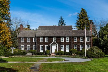 Doğu Hampton 'da yeşil çimenleri ve manzaralı balkonları olan eski Victoria tarzı ahşap binalara bakıyorum.