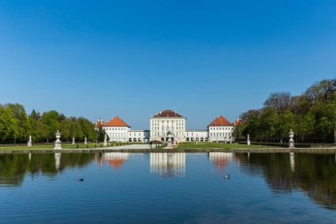 Münih, Almanya - 20 Nisan 2015: Nymphenburg Sarayı, Bavyera krallarının Münih, Almanya 'daki yazlık ikametgahı gölde yansıtılır. Bu saray yılda 300.000 ziyaretçiyi ağırlıyor..