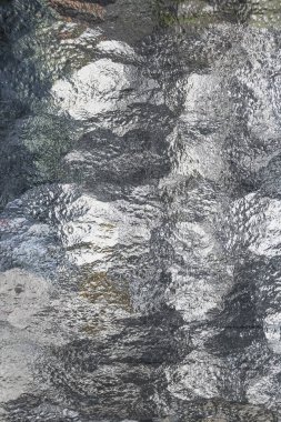 Yapılandırılmış camdaki yansıma deseni harmonik bir his verir.