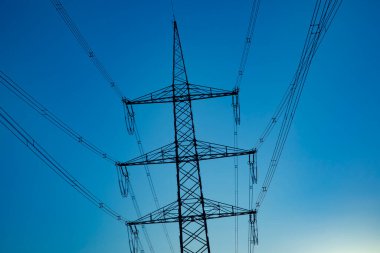 Gün batımında gökyüzünde elektrik direğini geçmek