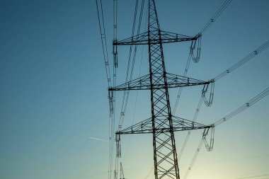 Gün batımında gökyüzünde elektrik direğini geçmek