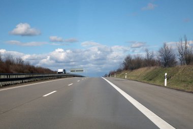 Güneşli bir günde, yumuşak bulutlu, boş bir Alman otoyolu.