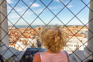 Venedik, İtalya - 7 Temmuz 2021: Kadın, San Marco Katedrali 'nin çatısına ve Venedik' in ufuk çizgisine manzaranın tadını çıkarıyor..