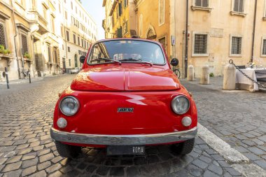 Roma, İtalya - 31 Temmuz 2021: Cobblestone Caddesi 'ndeki çeyrek Regla' da Roma 'da bir restoranın yanına park edilmiş klasik kırmızı Fiat 500. 1899 'da kurulan dünyaca ünlü İtalyan otomobil markası..