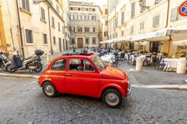 Roma, İtalya - 31 Temmuz 2021: Cobblestone Caddesi 'ndeki çeyrek Regla' da Roma 'da bir restoranın yanına park edilmiş klasik kırmızı Fiat 500. 1899 'da kurulan dünyaca ünlü İtalyan otomobil markası..