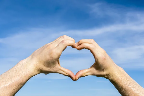 Heart shape with hand under blue sky — Stock Photo, Image