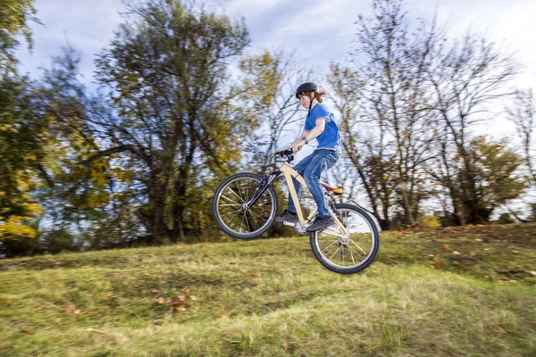 Menino pula sobre uma rampa com sua bicicleta de sujeira — Fotografia de Stock