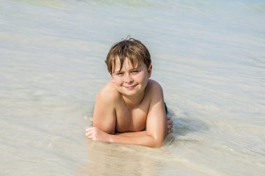 Çocuk sahilde yatan ve suyun sıcaklığını tadını