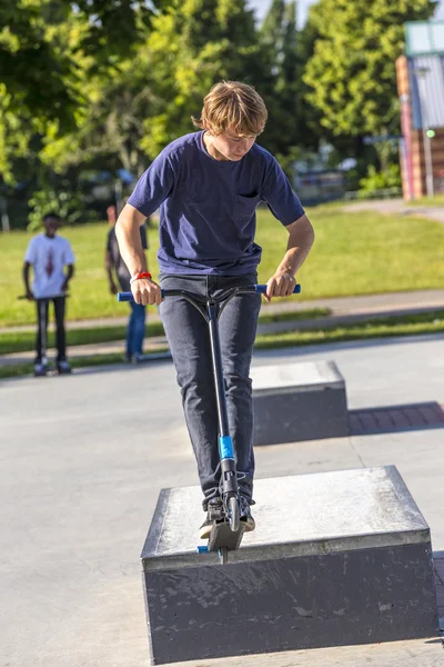 Menino se diverte montando sua scooter push — Fotografia de Stock