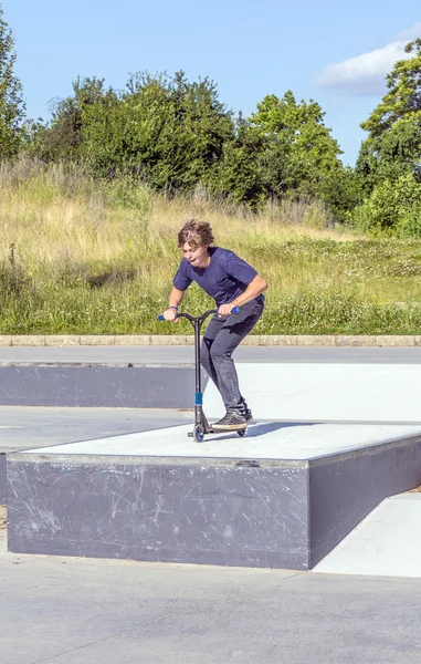 Menino se diverte montando sua scooter push — Fotografia de Stock