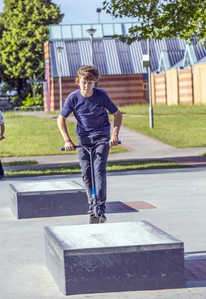 Menino se diverte montando sua scooter push — Fotografia de Stock