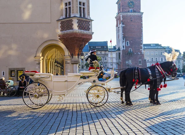 Carruajes de caballos frente a la iglesia Mariacki en la plaza principal de Kr — Foto de Stock