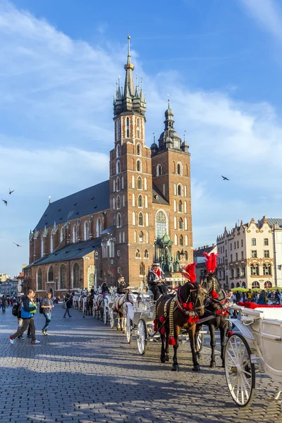 Carruajes de caballos frente a la iglesia Mariacki en la plaza principal de Kr —  Fotos de Stock