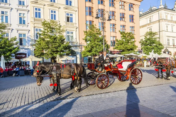 Carruajes de caballos frente a la iglesia Mariacki en la plaza principal de Kr —  Fotos de Stock