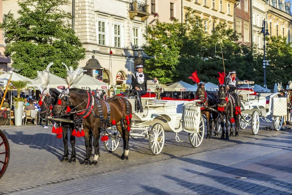 Carruagens de cavalo em frente à igreja Mariacki na praça principal de Kr — Fotografia de Stock