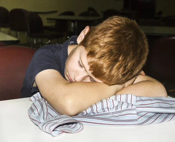 Jonge jongen slaapt met hoofd op de tafel — Stockfoto