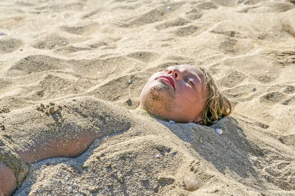 Ung flicka är täckt av sand på stranden — Stockfoto