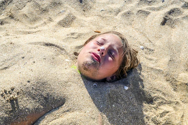 Giovane ragazza è coperta di sabbia in spiaggia — Foto Stock