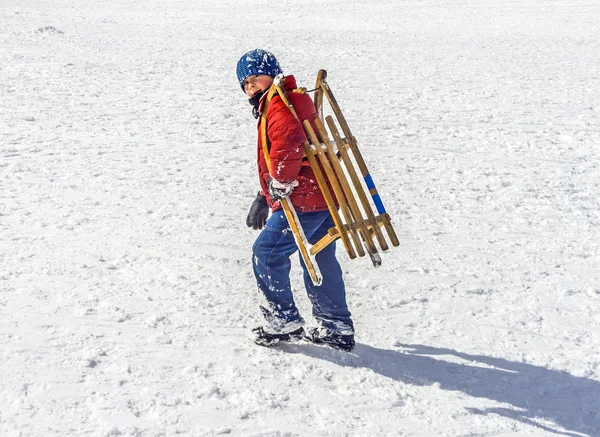 男孩运载他的雪橇在小山上 — 图库照片