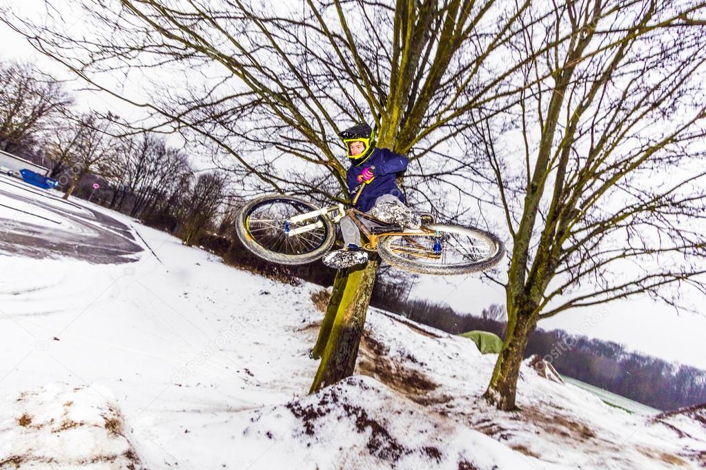 boy jumping with his bike over a ramp in snow