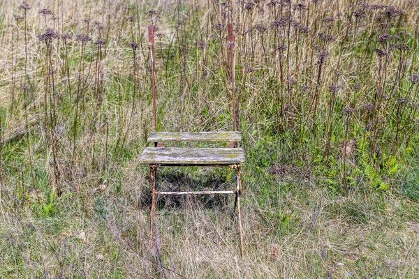 Vieja silla de madera podrida en un prado — Foto de Stock