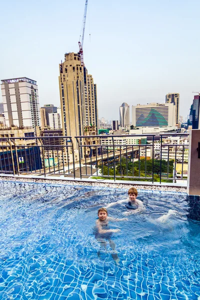 Boys swim in an open air pool with beautiful view to the skyscra — Stock Photo, Image