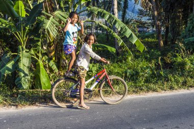 young girls enjoy riding on a bicycle and make jokes 