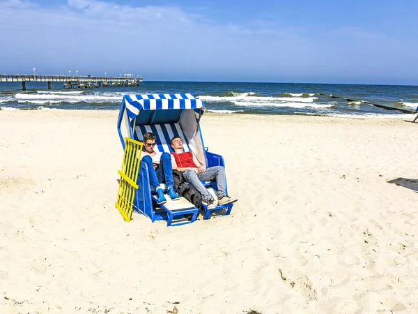 La gente disfruta del baño de sol en la silla de playa de mimbre techada —  Fotos de Stock