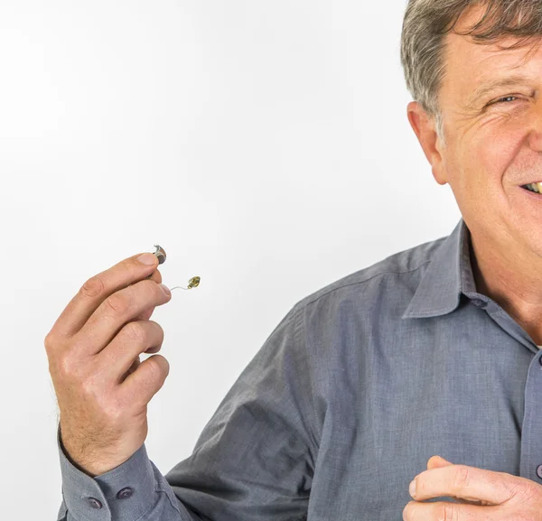 Hombre serio con camisa manejando su audífono —  Fotos de Stock