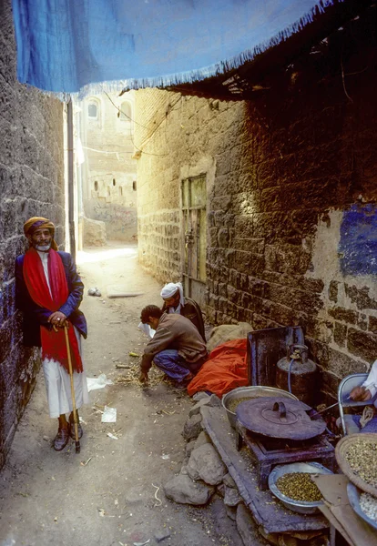 Anciano en un camino angosto con un puesto de comida vendiendo nueces asadas — Foto de Stock