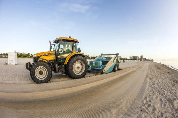 Hombre prepara la playa temprano en la mañana con el tractor —  Fotos de Stock