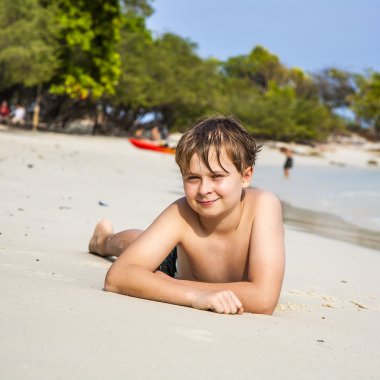 Çocuk kumlu plajda yatıyor ve ince sıcak kum sahiptir