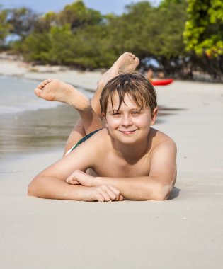 Çocuk kumlu plajda yatıyor ve ince sıcak kum sahiptir