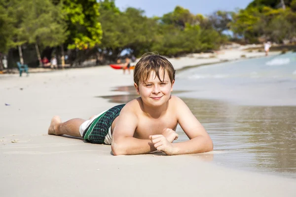 Αγόρι βρίσκεται στην αμμώδη παραλία και απολαμβάνει την ψιλή άμμο ζεστό — Φωτογραφία Αρχείου