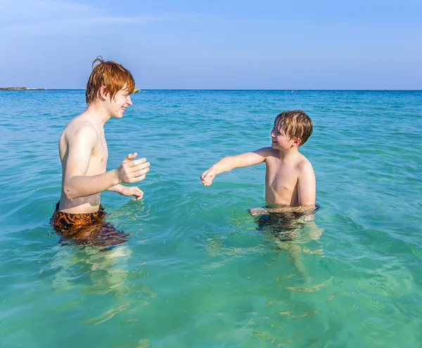 Fratelli stanno godendo l'acqua calda e limpida Foto Stock