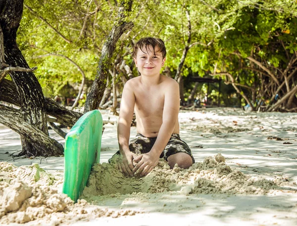 幸せな若い少年は、ビーチの砂を掘る — ストック写真