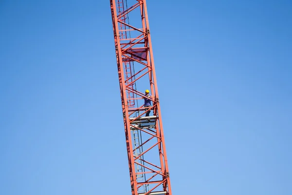 Worker climbs a tall crane — Stock Photo, Image
